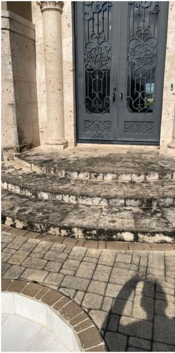 A shadow of a person is cast on the steps of a building.