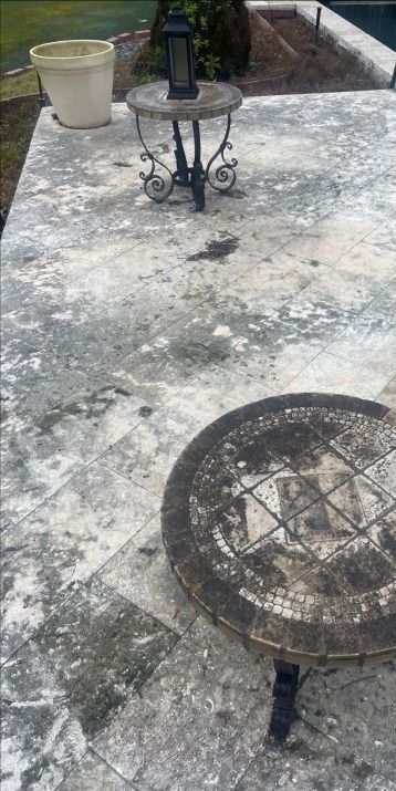 A dirty patio with a table and a lantern on it.