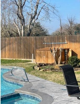 A swimming pool with a wooden fence in the background