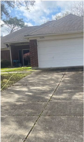 A white garage door is open in front of a brick house.