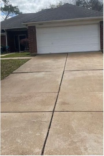 A brick house with a white garage door and a concrete driveway in front of it.