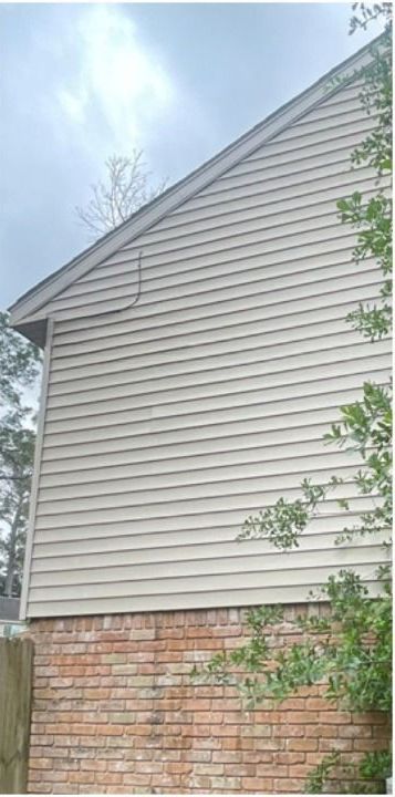 A brick house with a white siding and a roof.