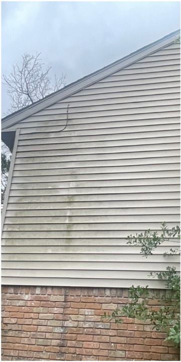 A house with a dirty siding and a brick wall.