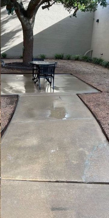 A patio with a table and chairs under a tree.
