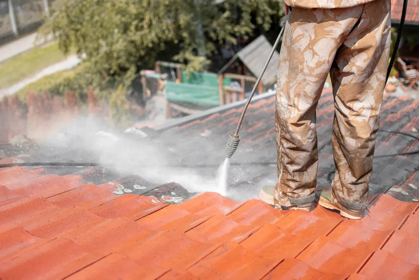 A man is cleaning a roof with a high pressure washer.