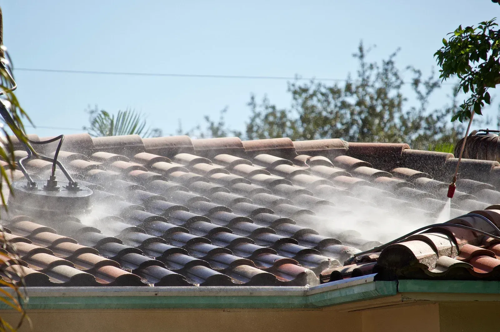 A person is cleaning the roof of a house with a pressure washer.
