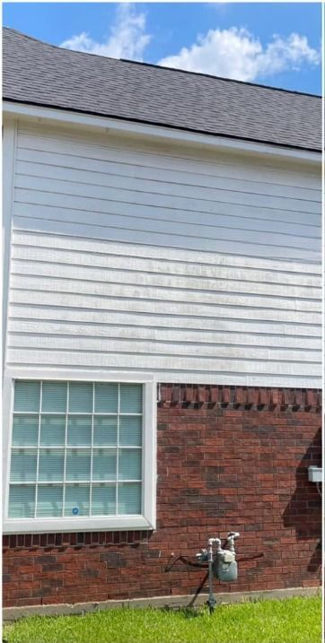 A brick house with a white siding and a window.
