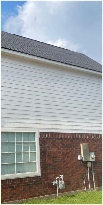 A brick house with a white siding and a gray roof.