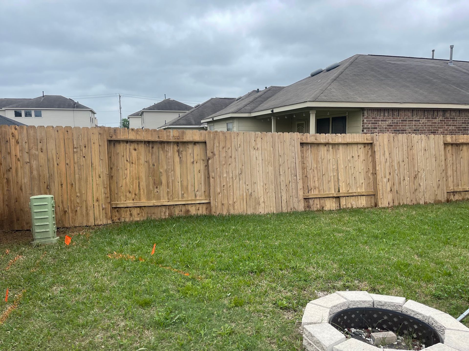 A wooden fence is in the backyard of a house.