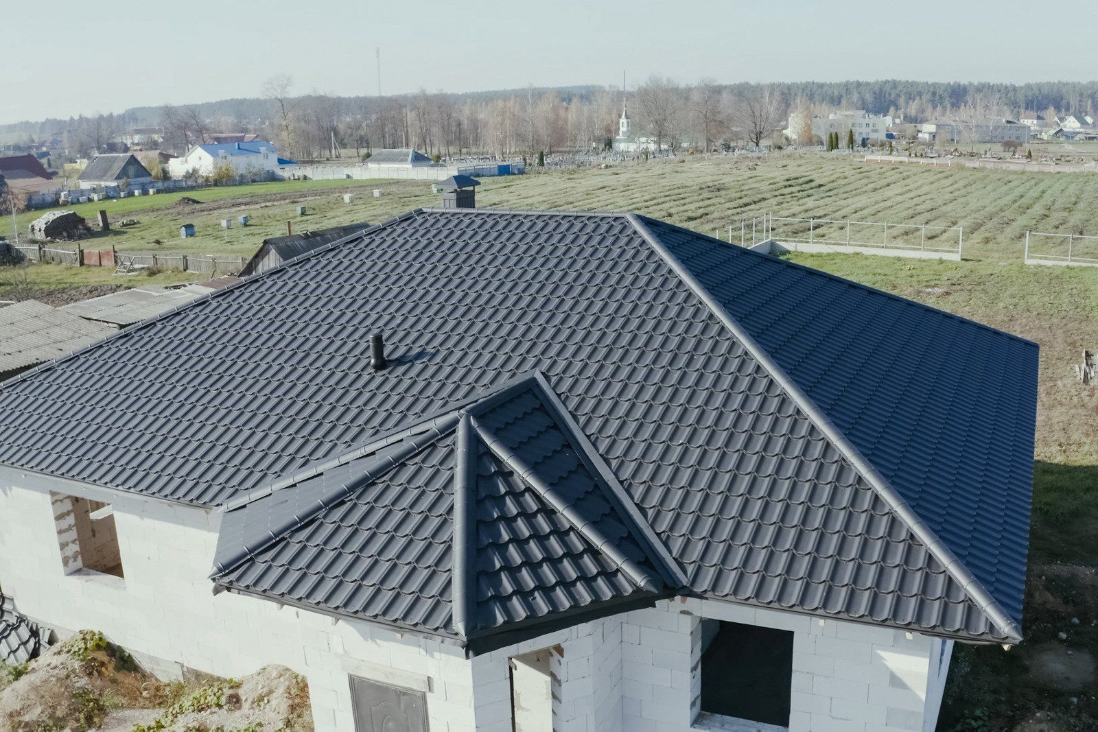 A man is cleaning the roof of a house with a high pressure washer.