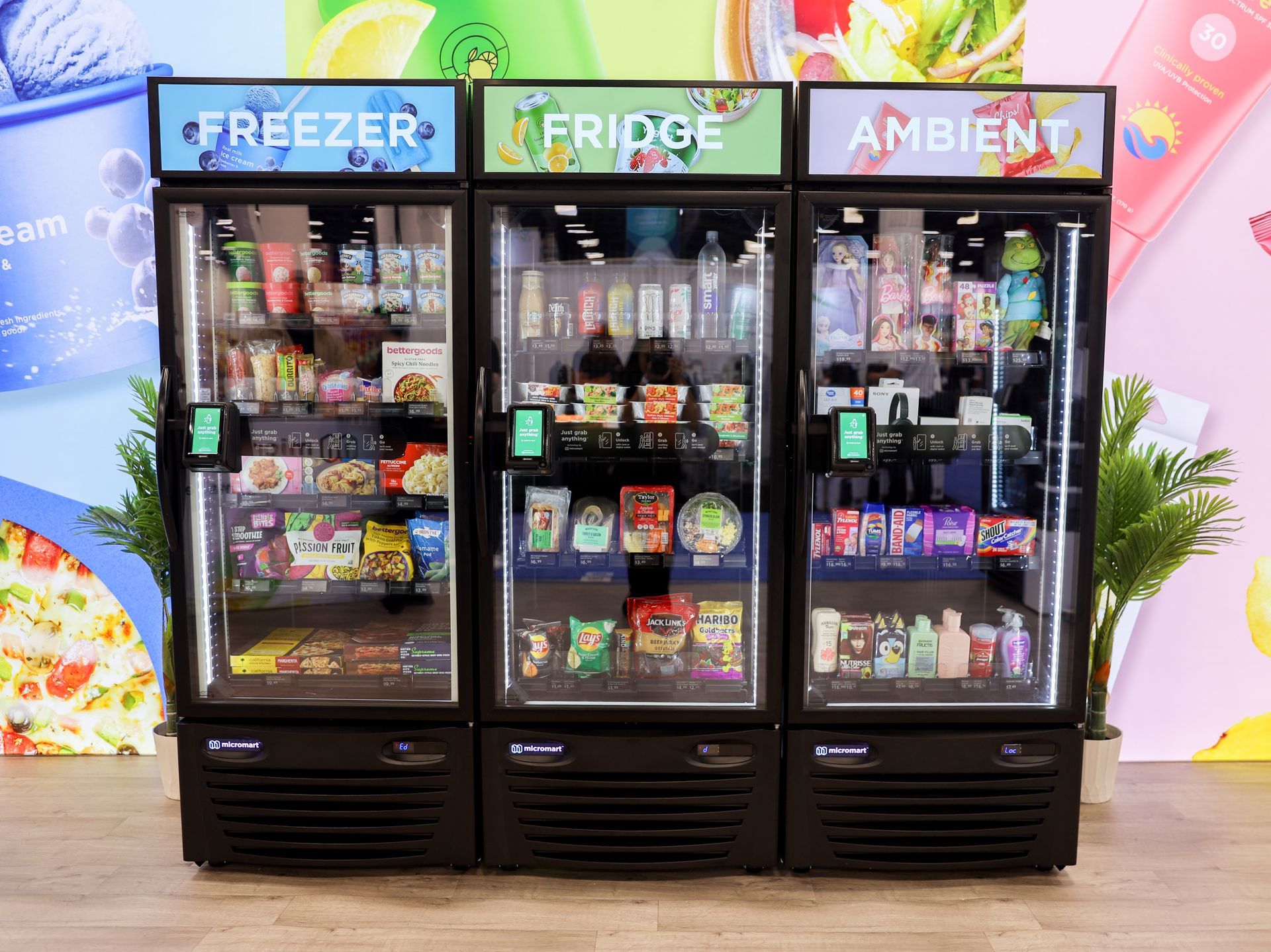 Three side-by-side vending machines labeled Freezer, Fridge, and Ambient, filled with various snacks and drinks.