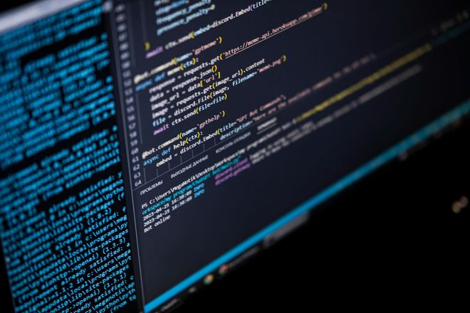 A computer monitor displays lines of colorful software code against a dark background.