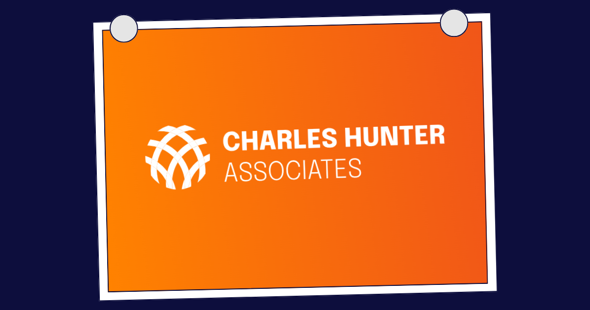 Four people, including one with glasses, reviewing charts at a table in a bright office.