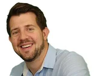 Smiling man with brown hair and stubble in a light blue button-down shirt.