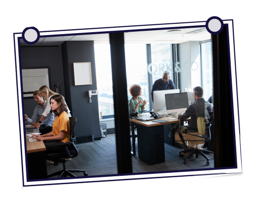 Woman waving at a yellow computer screen; man smiles and leans in. They are in a well-lit room.