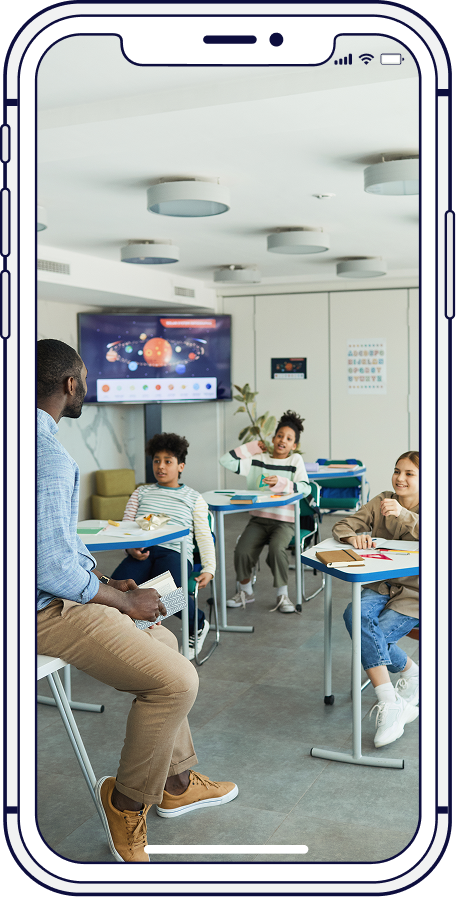 Teacher in classroom, teaching students. Students are sitting and standing near desks.