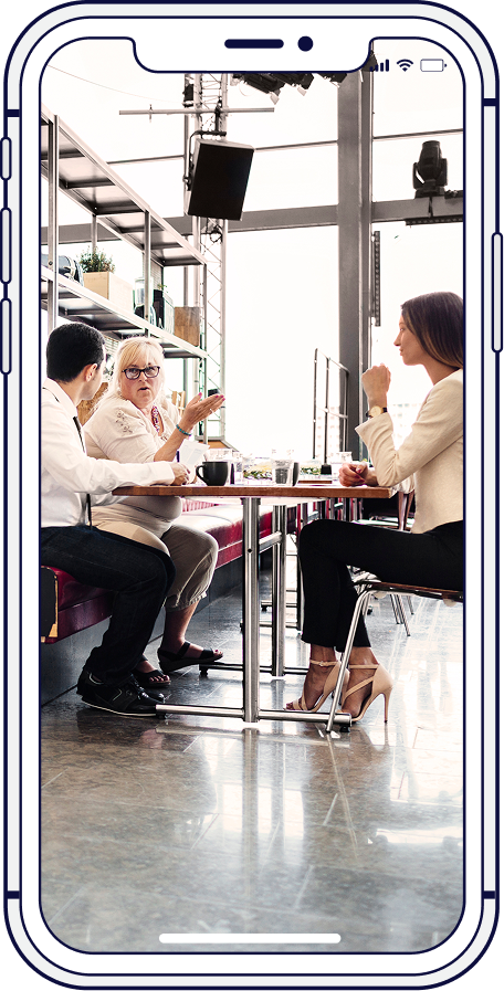 Teacher with students in a classroom, one child raising their hand near a screen.