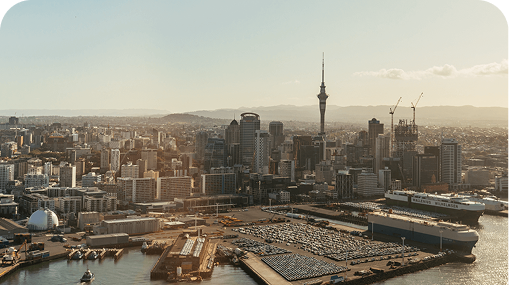 Auckland, New Zealand skyline with the Sky Tower prominent, harbor, and ships.