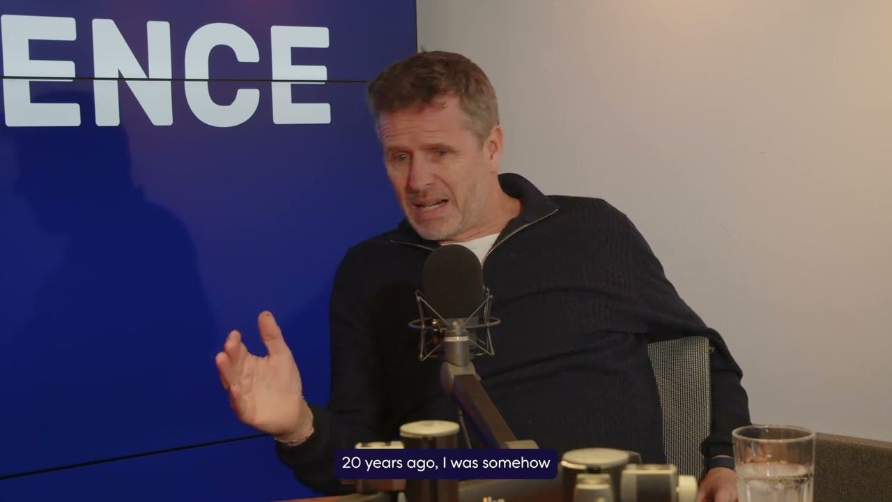 Man gesturing during a podcast, seated near a microphone. The backdrop displays "ENCE."