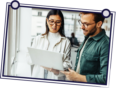 People in a meeting around a table, one man standing holding a document.