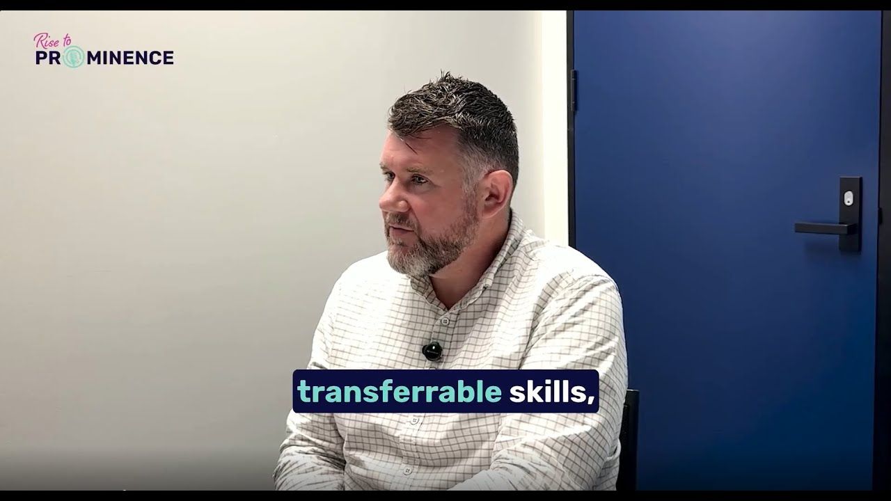 Man speaking, text reads "transferrable skills," seated against a white wall and blue door backdrop.
