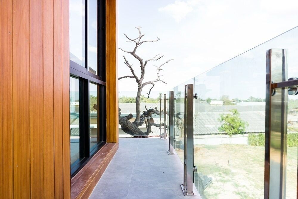 A Balcony With a Glass Railing and a Tree in the Background — Kincumber Glass & Glazing in Kincumber, NSW