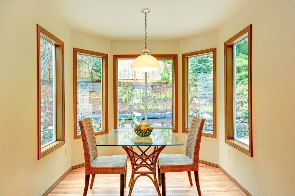 A Dining Room With a Glass Table and Chairs and Lots of Windows — Kincumber Glass & Glazing in Kincumber, NSW
