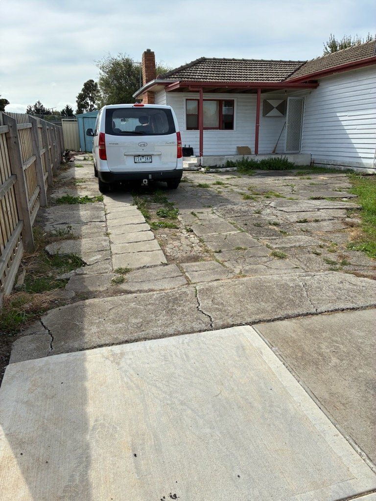 White van parked on cracked concrete driveway in front of a house.