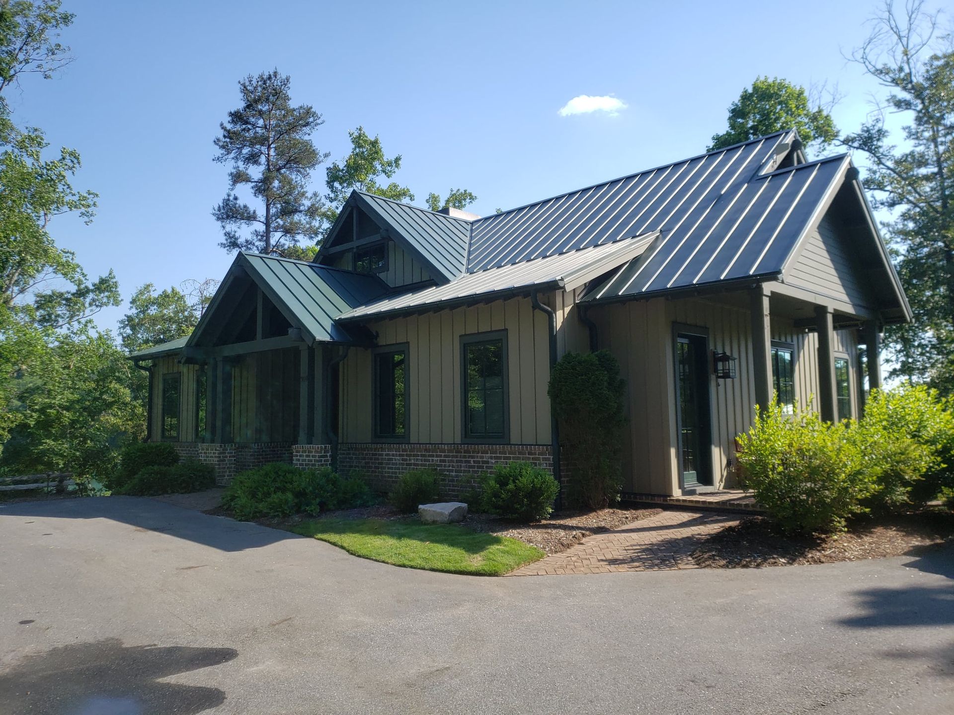 A house with a metal roof is surrounded by trees