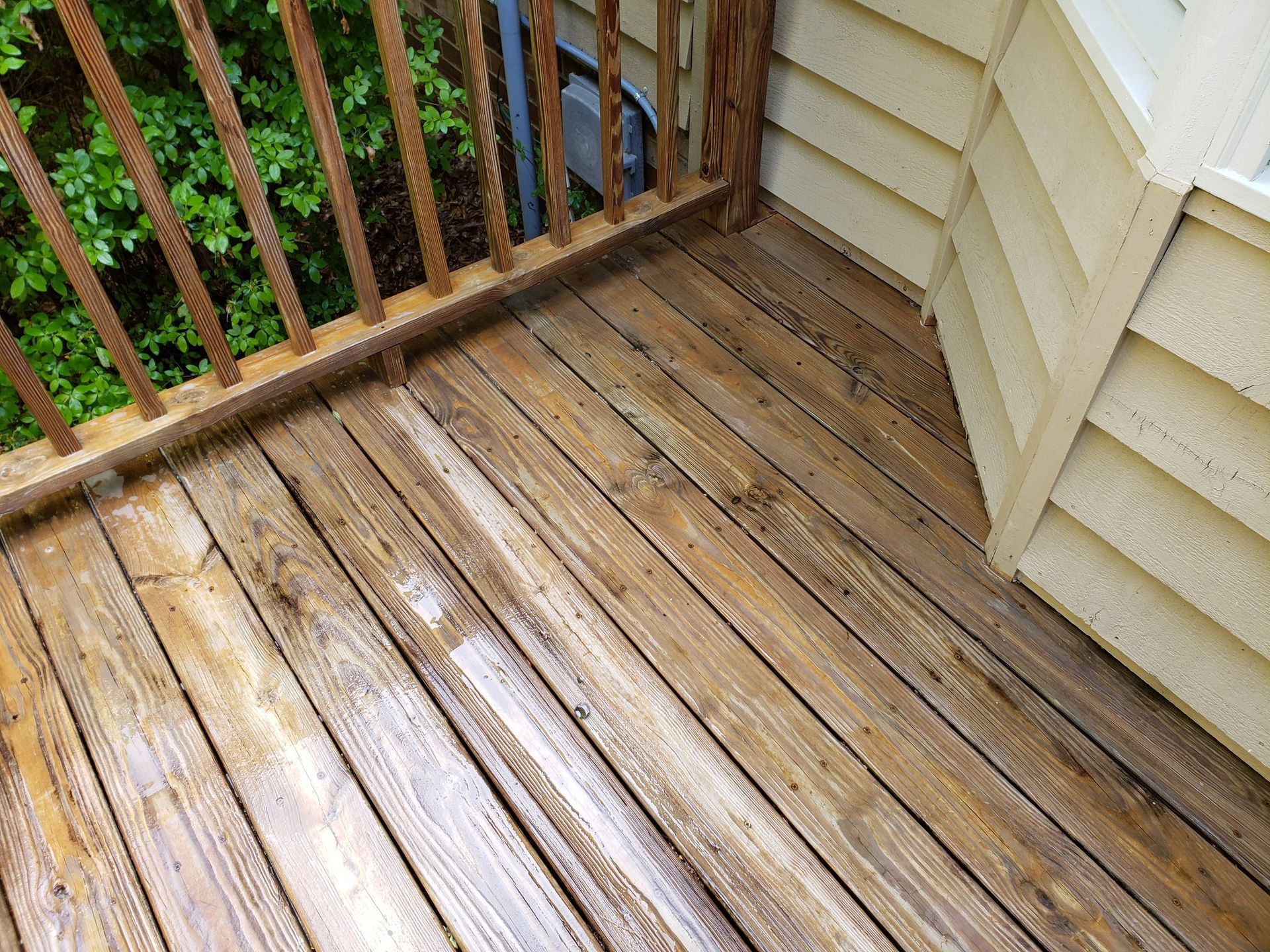 A wooden deck with a railing next to a house.