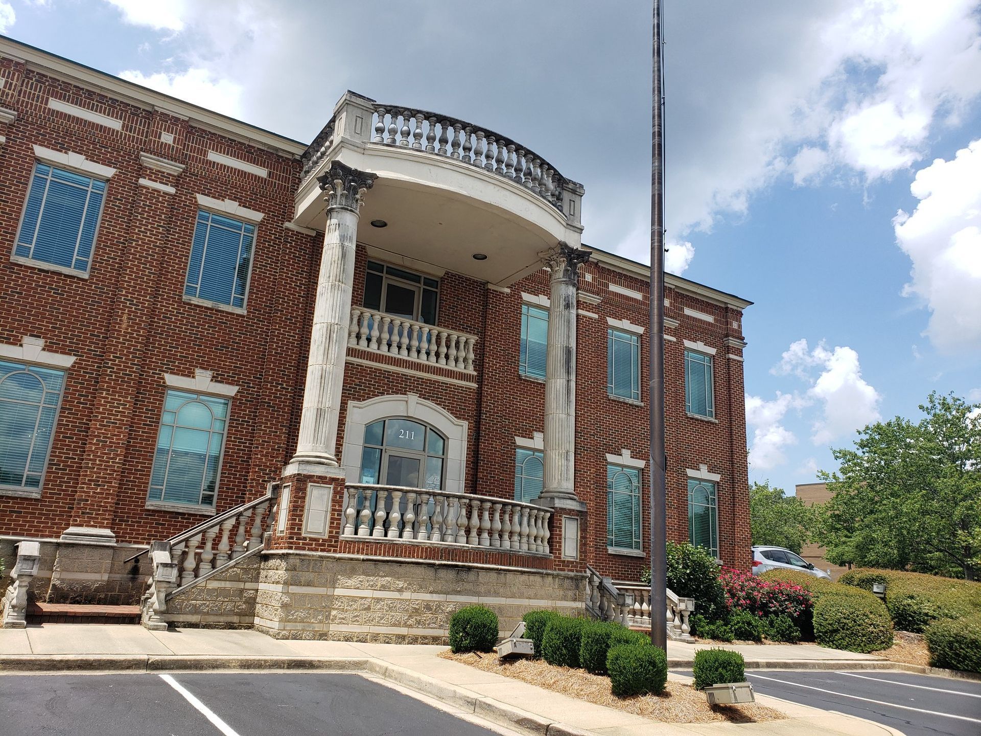 A large brick building with a balcony and a parking lot in front of it.
