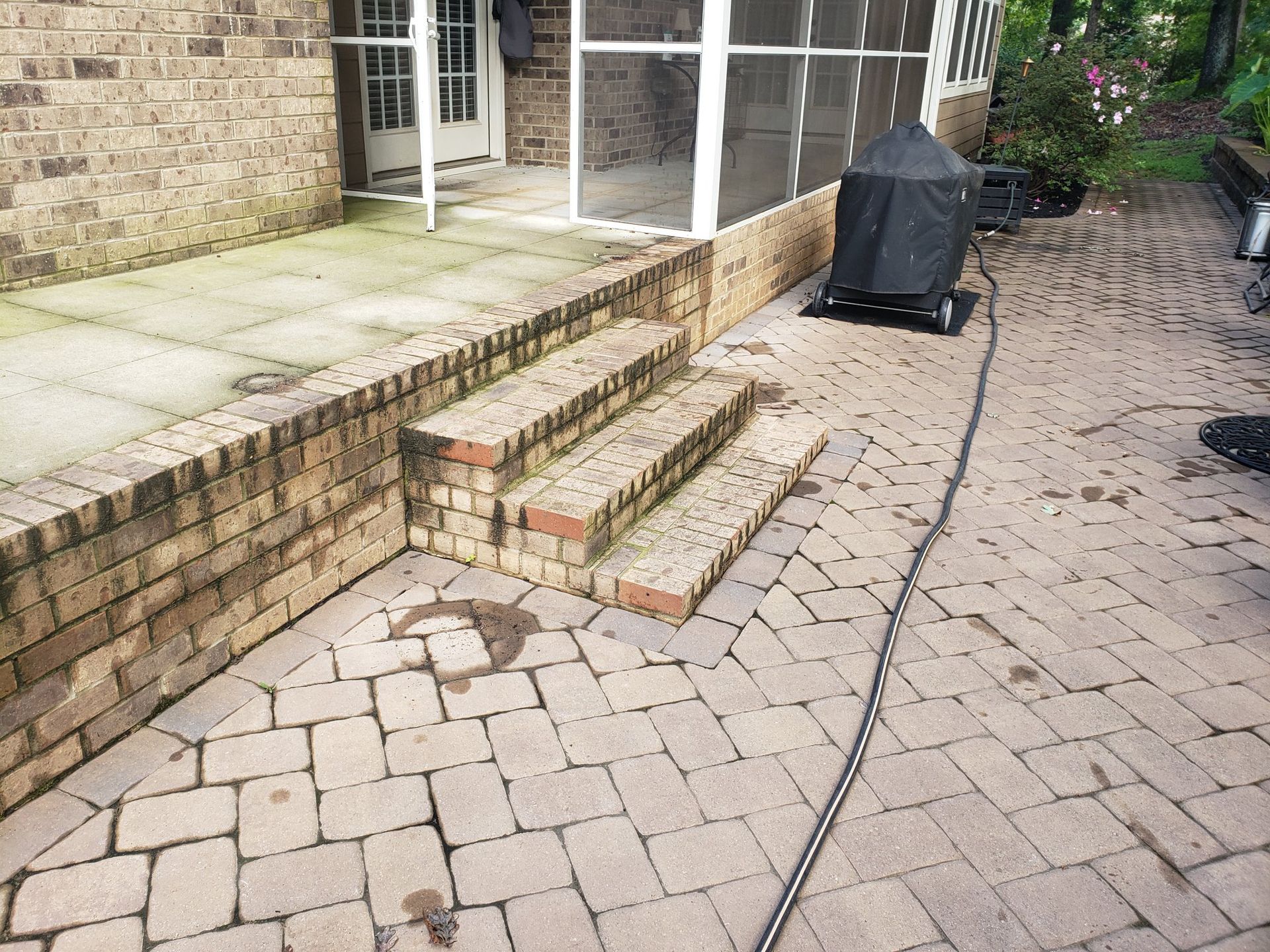 A brick patio with stairs leading up to a screened in porch.