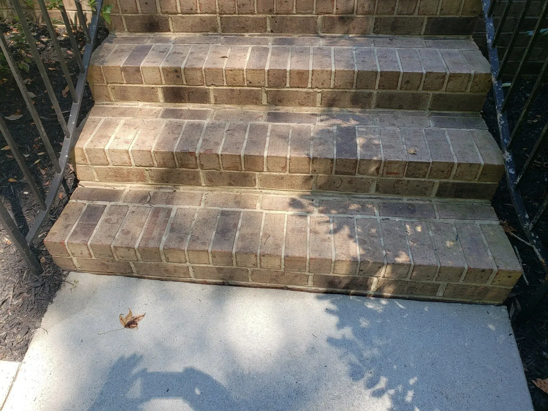 A set of brick stairs leading up to a concrete walkway.