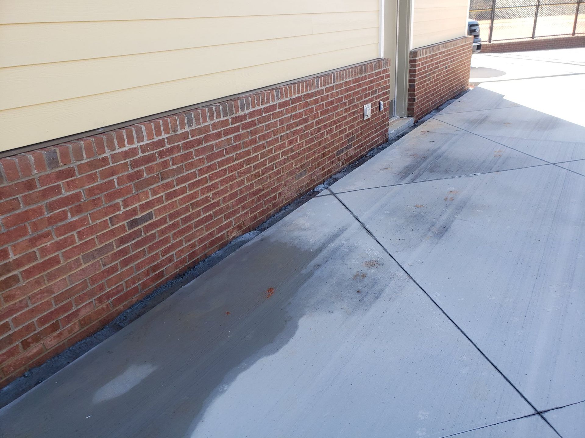 A brick building with a concrete sidewalk in front of it.