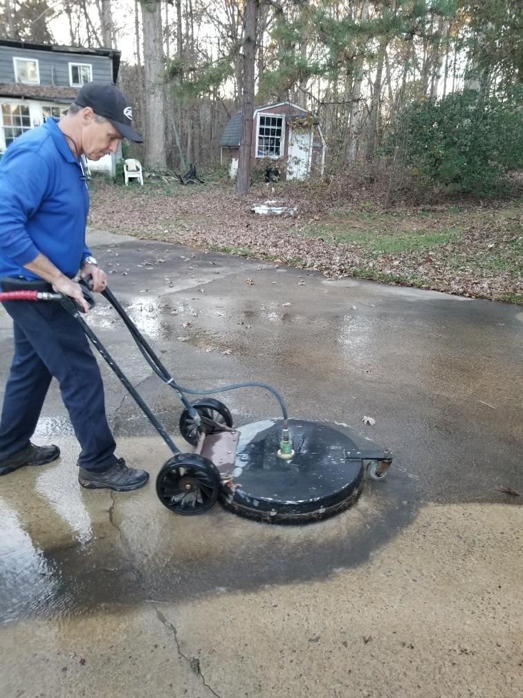 A man is using a machine to clean a driveway.