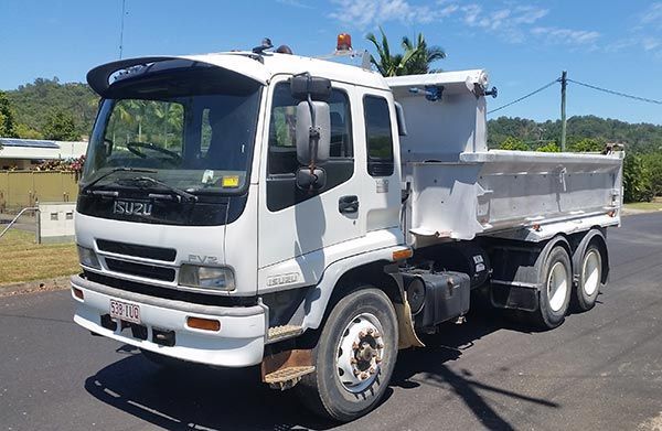 A white dump truck is parked on the side of the road.