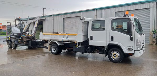 A white truck with a trailer attached to it is parked in front of a building.