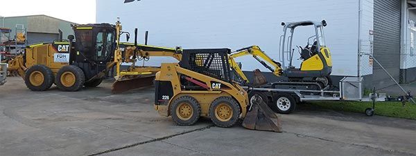 A couple of construction vehicles are parked next to each other in a parking lot.