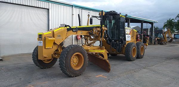 A yellow tractor is parked in front of a building.