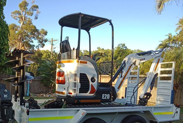 A small excavator is parked on the back of a trailer.