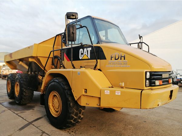 A cat dump truck is parked in a parking lot