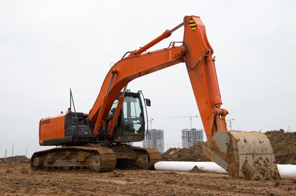 A large orange excavator is working on a construction site.
