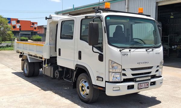 A white truck is parked in a parking lot in front of a building.