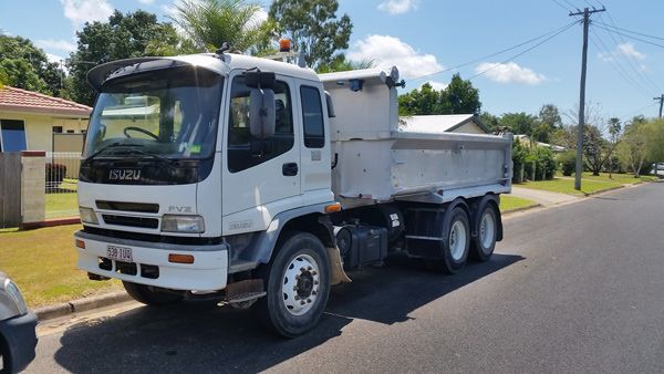 A white dump truck is parked on the side of the road.