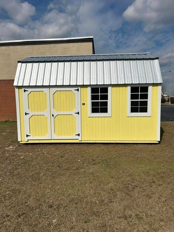 Yellow shed with white trim, metal roof, and two windows.