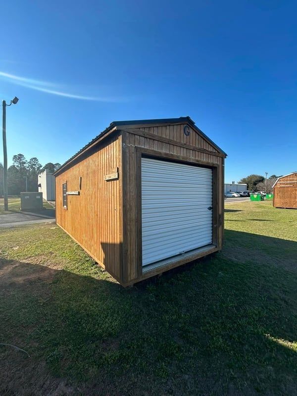 Gray shed with black doors and white-framed windows, against a gray sky.