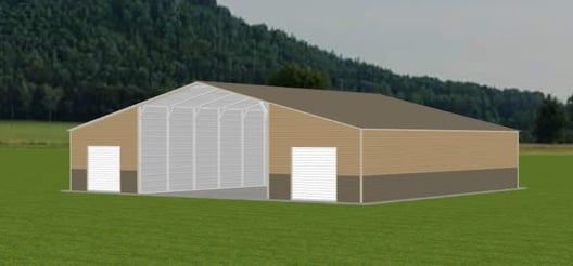 A tan warehouse-style building with white doors and a large open front, set in a grassy field.