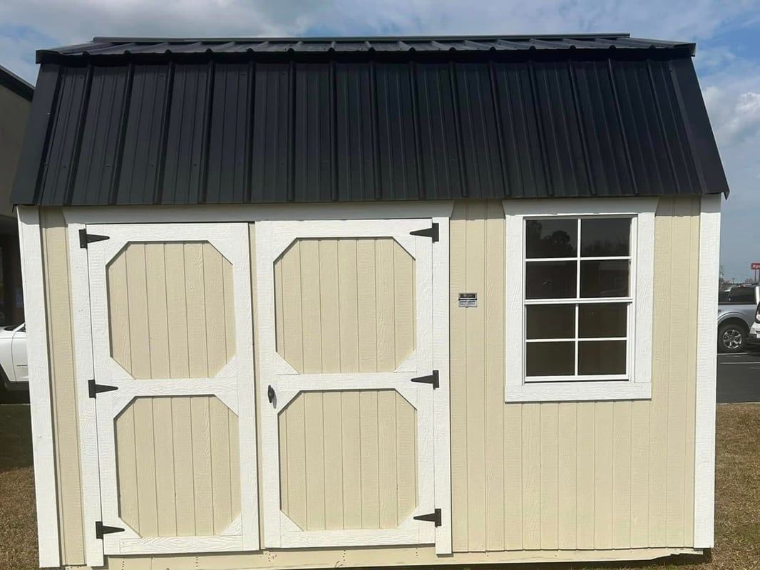 Tan shed with black roof, two doors, and a window; outdoors.