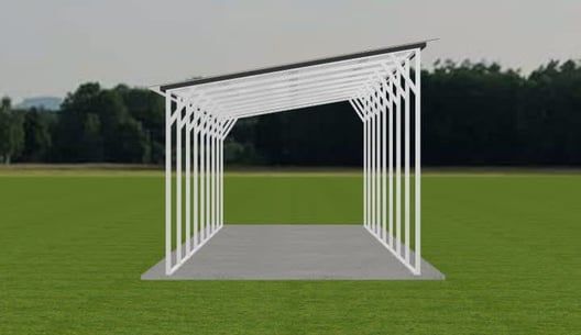 White metal carport on a concrete slab, set on a green field. A dark angled roof covers the structure.