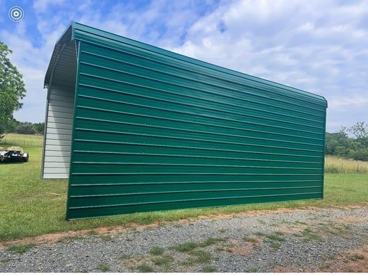 Green metal storage building in a grassy field.